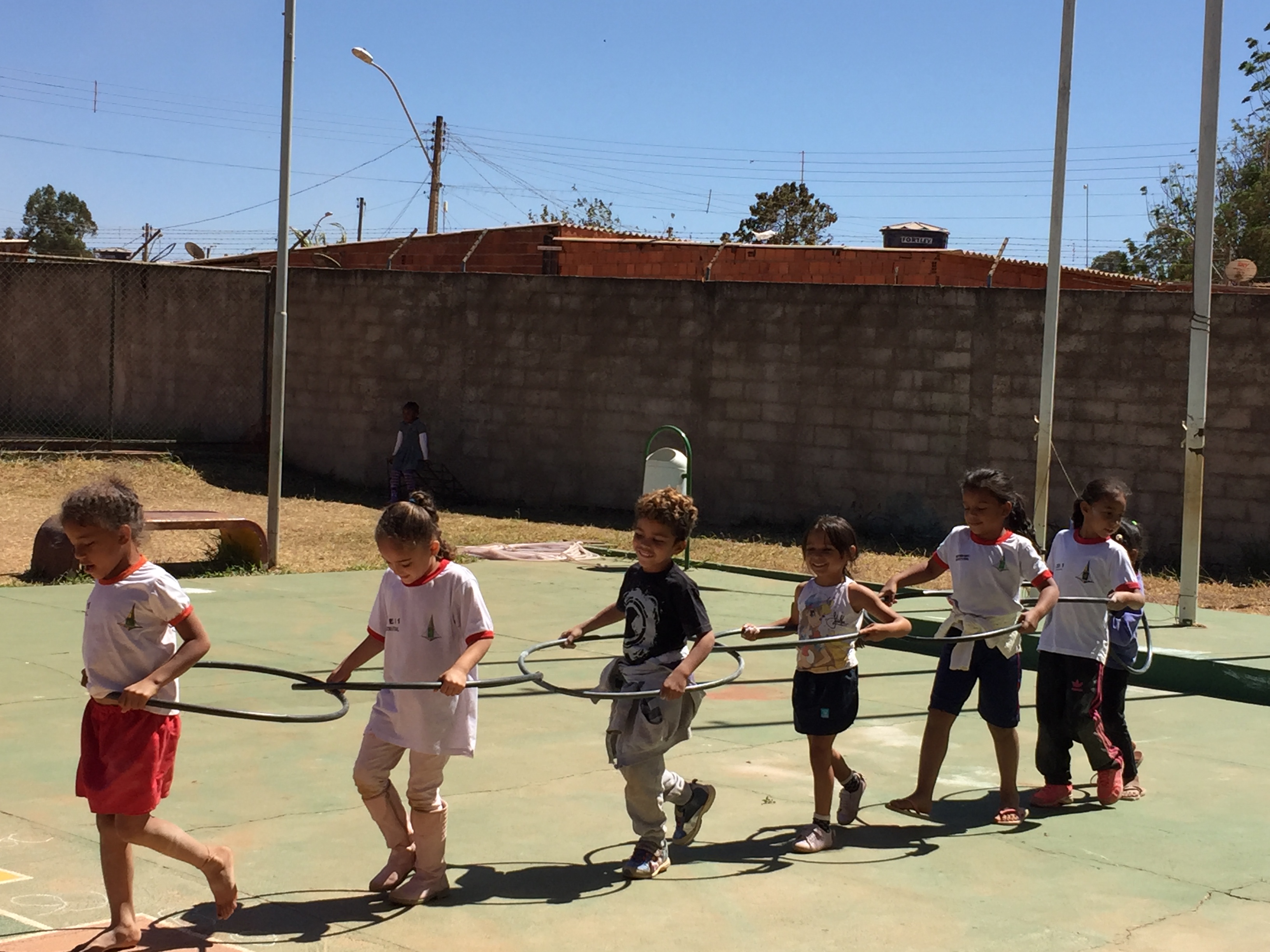 Crianças brincando de trem com bambolês.